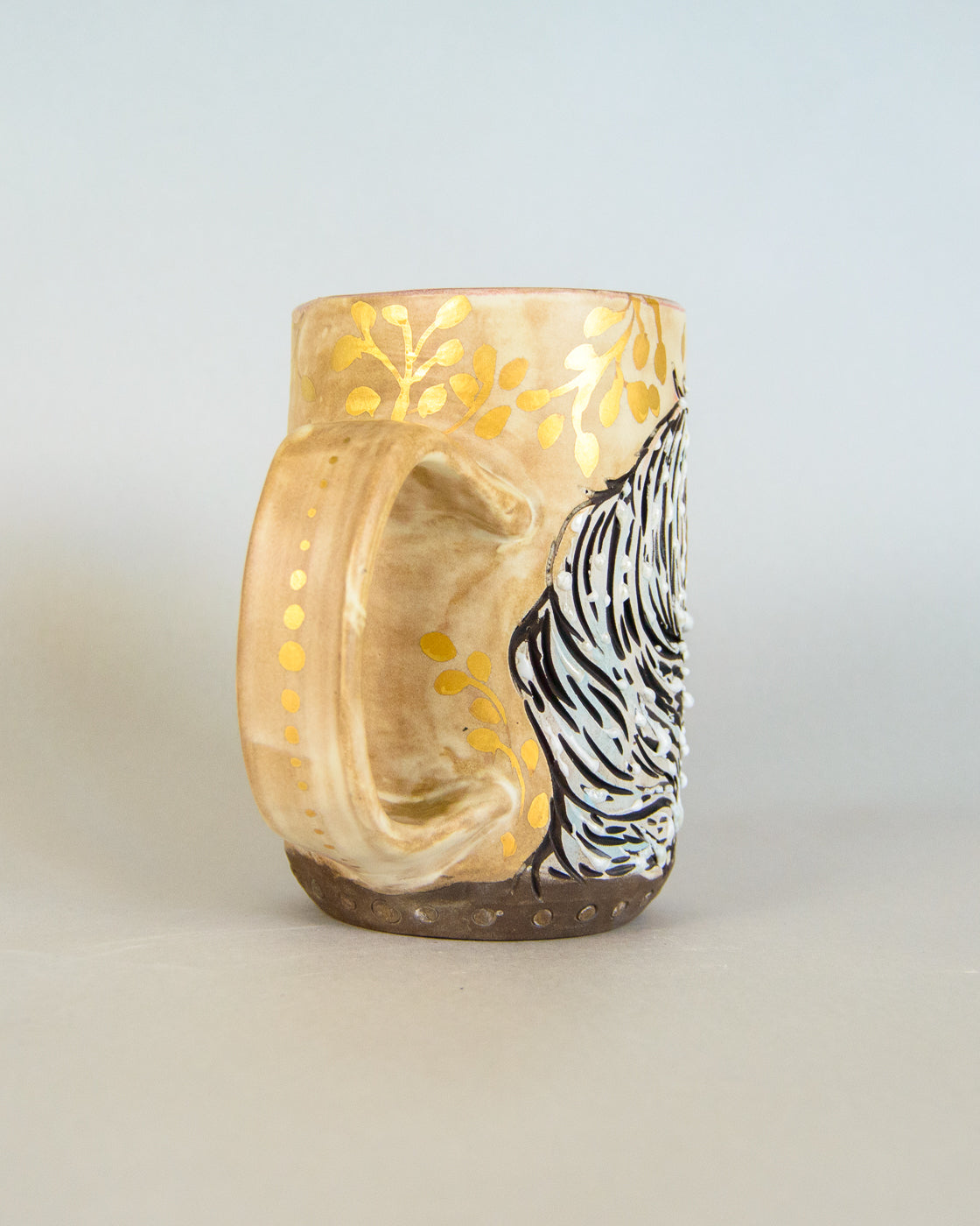 ceramic mug with unicorn design and gold accents on a light gray background