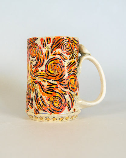 Decorative ceramic mug with orange and black spiral pattern on a light gray background