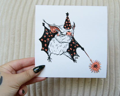 Black, white, and pink Illustration of a bat wearing a witch hat with a magic wand, casting a spell on a spider. 