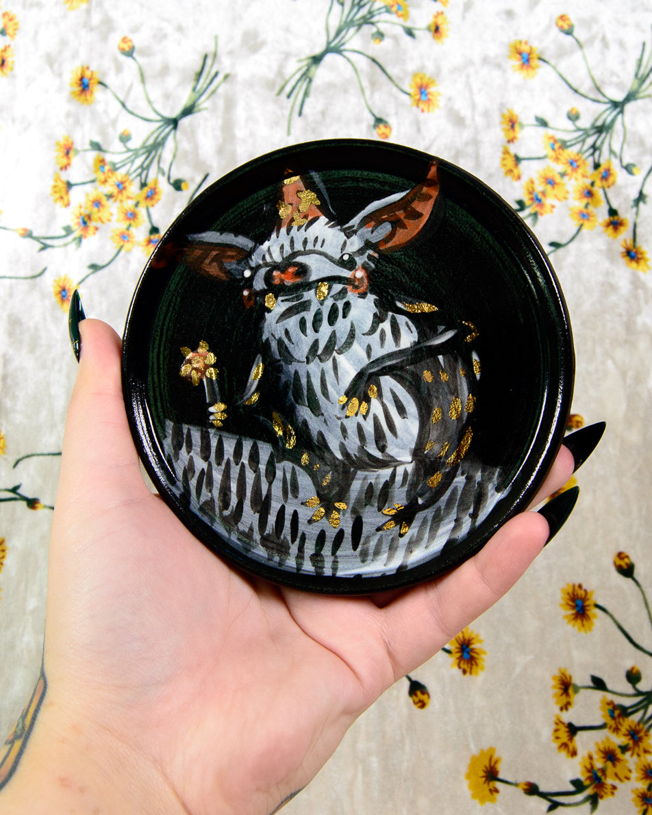 hand painted ceramic coaster with a cartoon bat wizard holding a flower