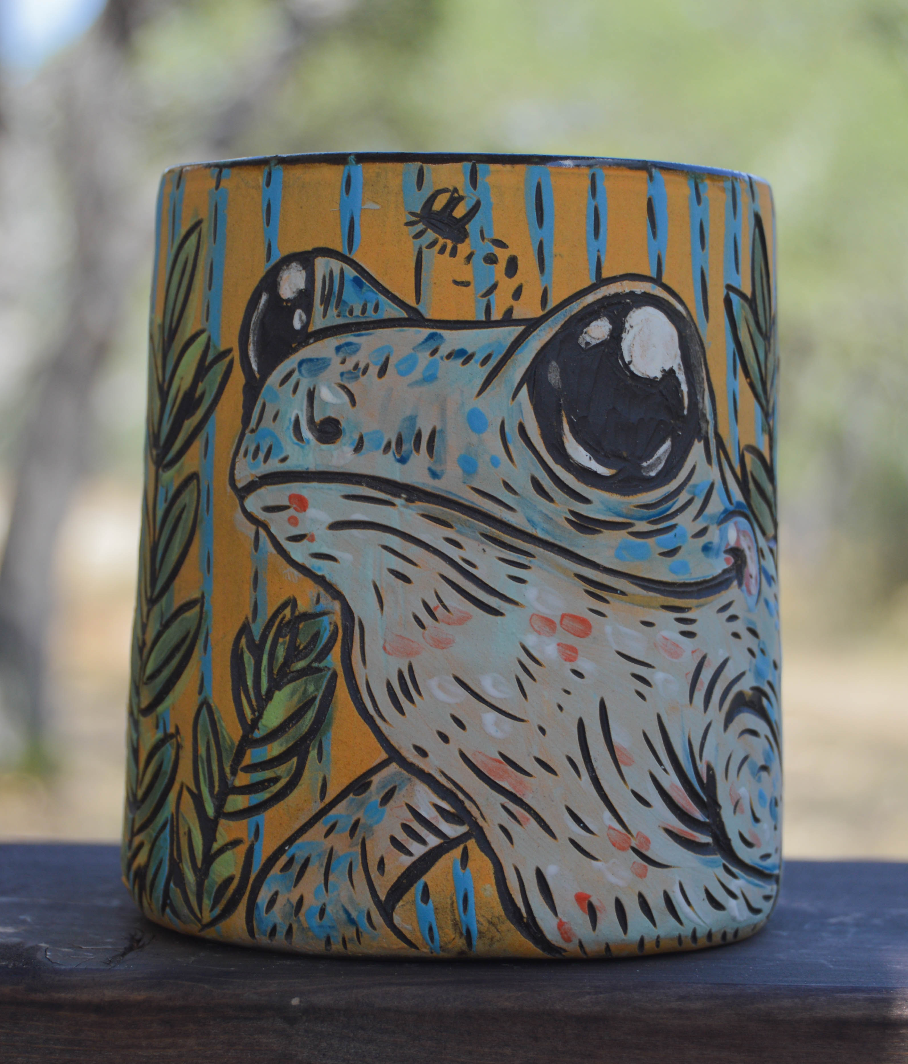 Ceramic mug with a stylized frog design on a natural background